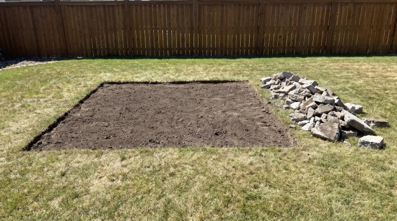 Bare graded dirt where a concrete patio was removed in a Meridian, Idaho backyard, with broken concrete chunks stacked neatly along one edge