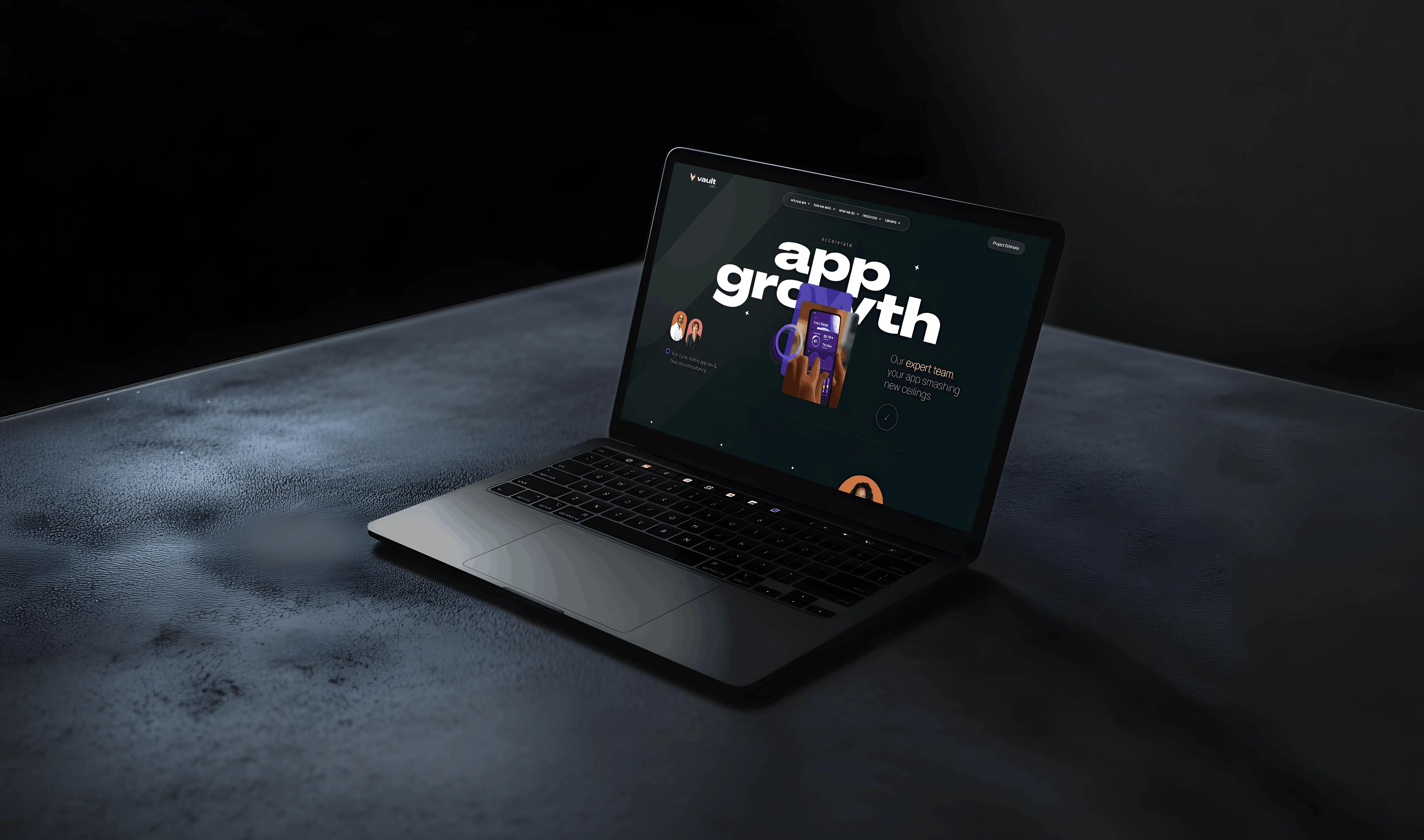 Laptop on dark textured surface displaying a webpage with the text app growth and a hand holding a smartphone.