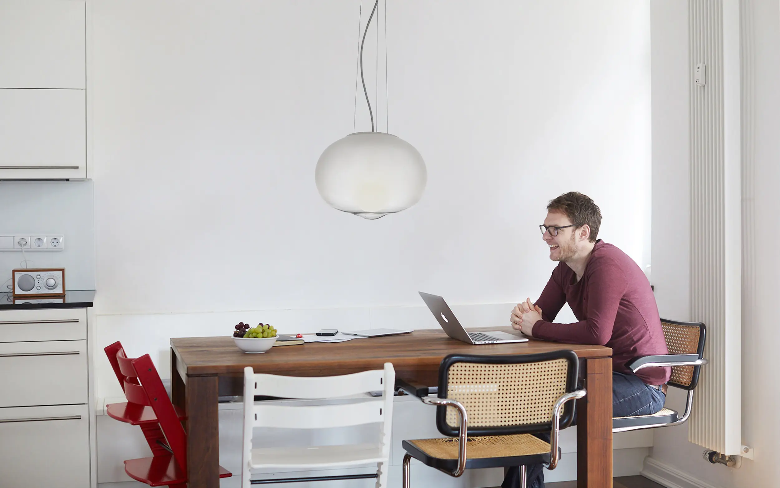 Polastern Energie Gründer Simon sitzt an einem Esstisch mit Laptop und lacht