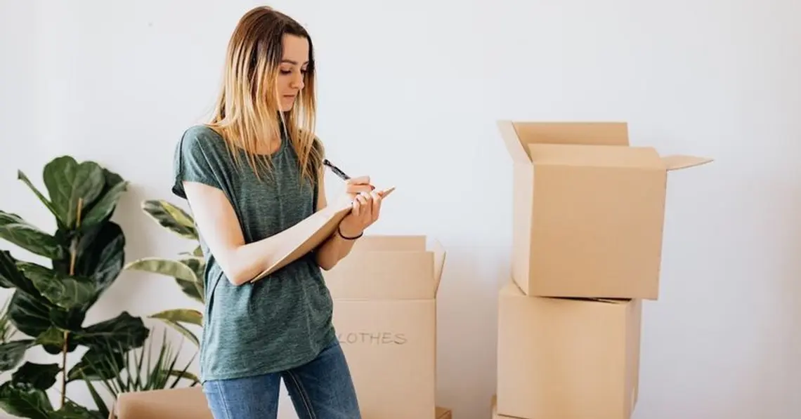 Frau vor Umzugskartons mit Checkliste