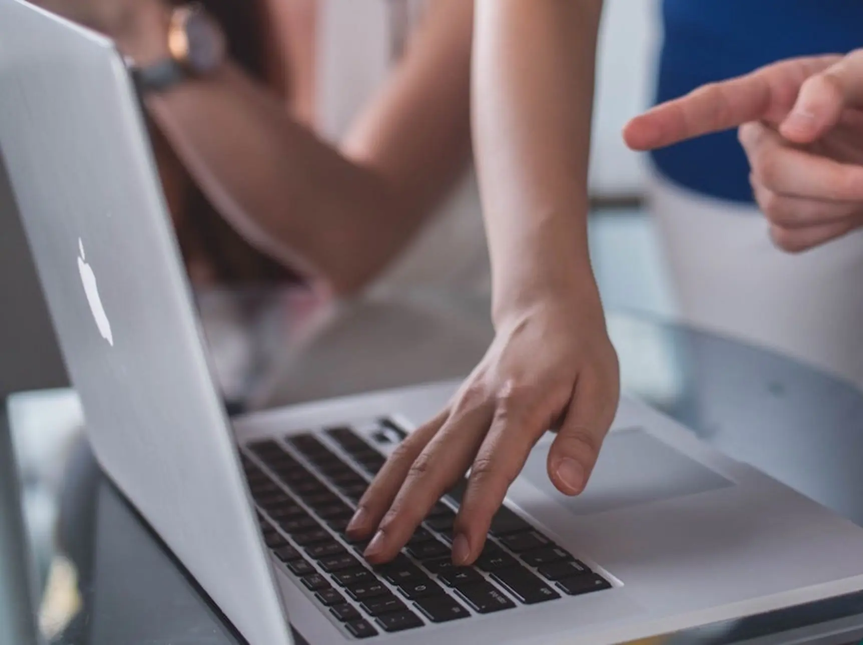 Hände zeigen auf Laptop