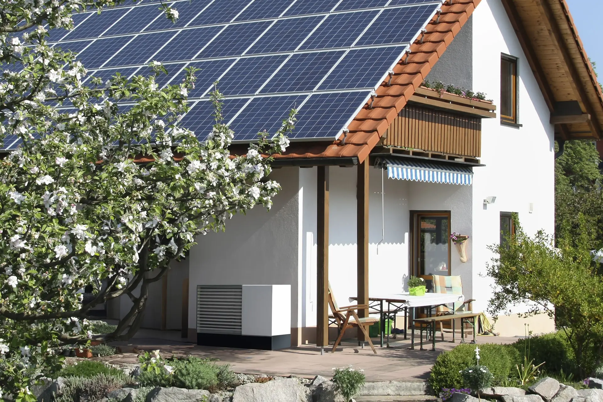 Ein Haus mit Solarpanelen auf dem Dach und Wärmepumpe auf der Veranda.