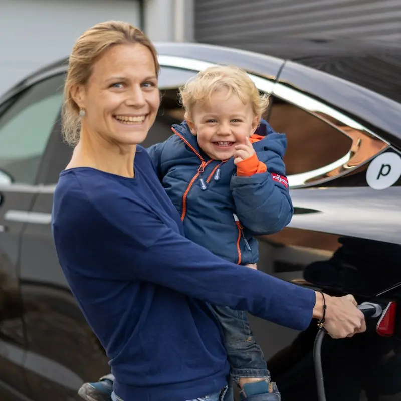 Frau mit Kind vor Elektroauto
