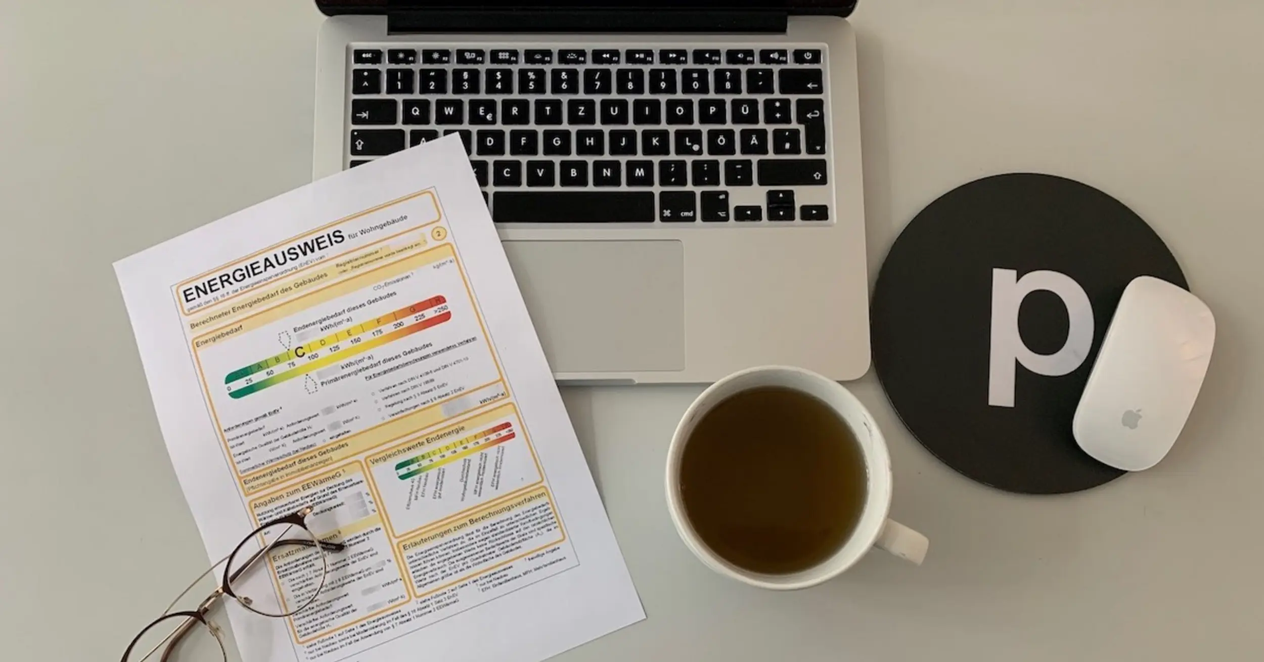 Energieausweis auf Laptop mit Kaffee und Brille