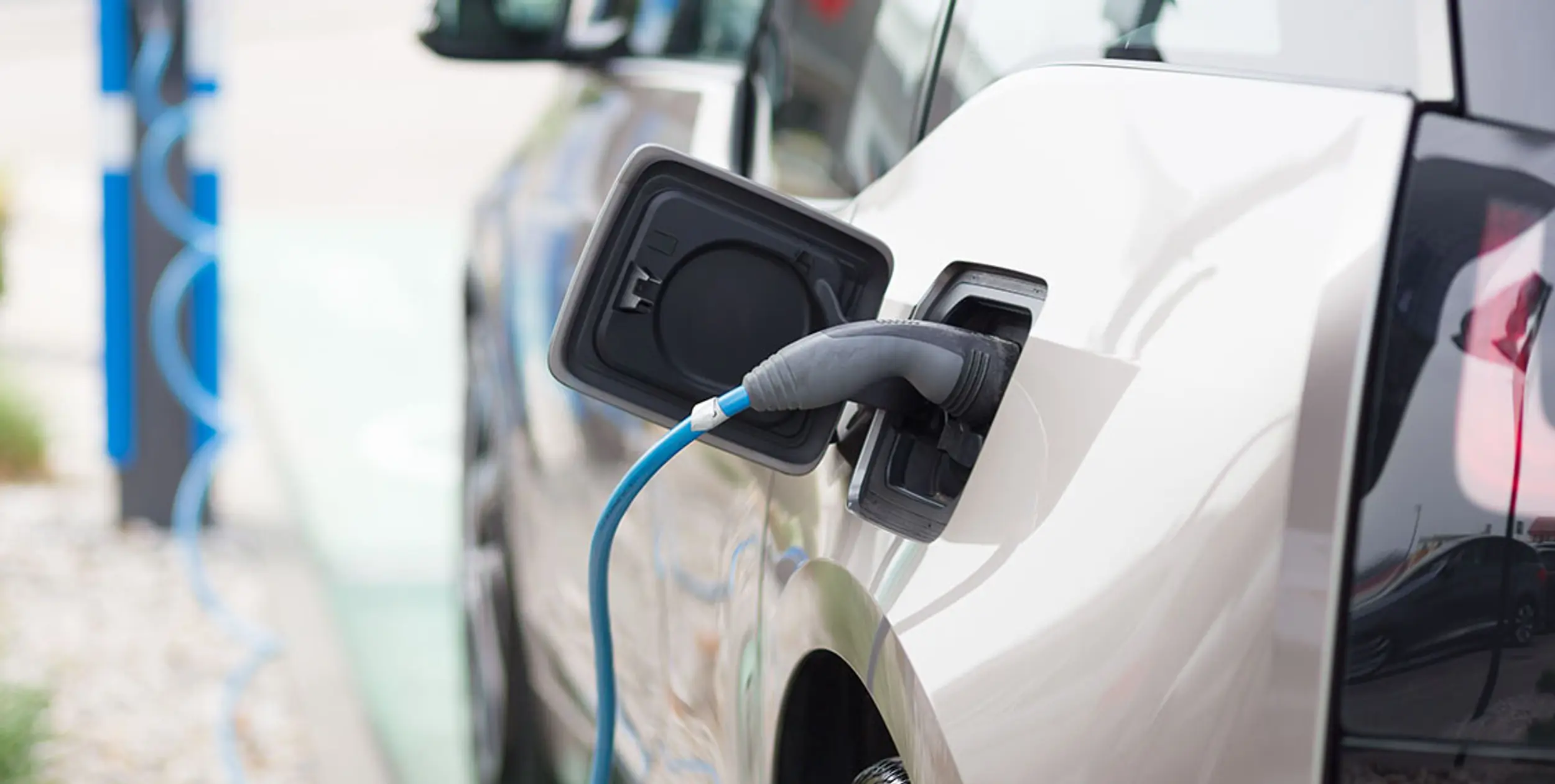 Eine Hand steckt ein Ladekabel in den Tank eines E-Autos