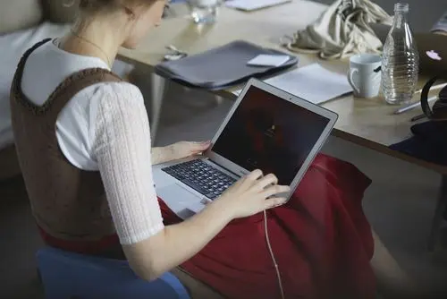 Frau in Dirndl tippt etwas auf einen Laptop auf ihren Beinen