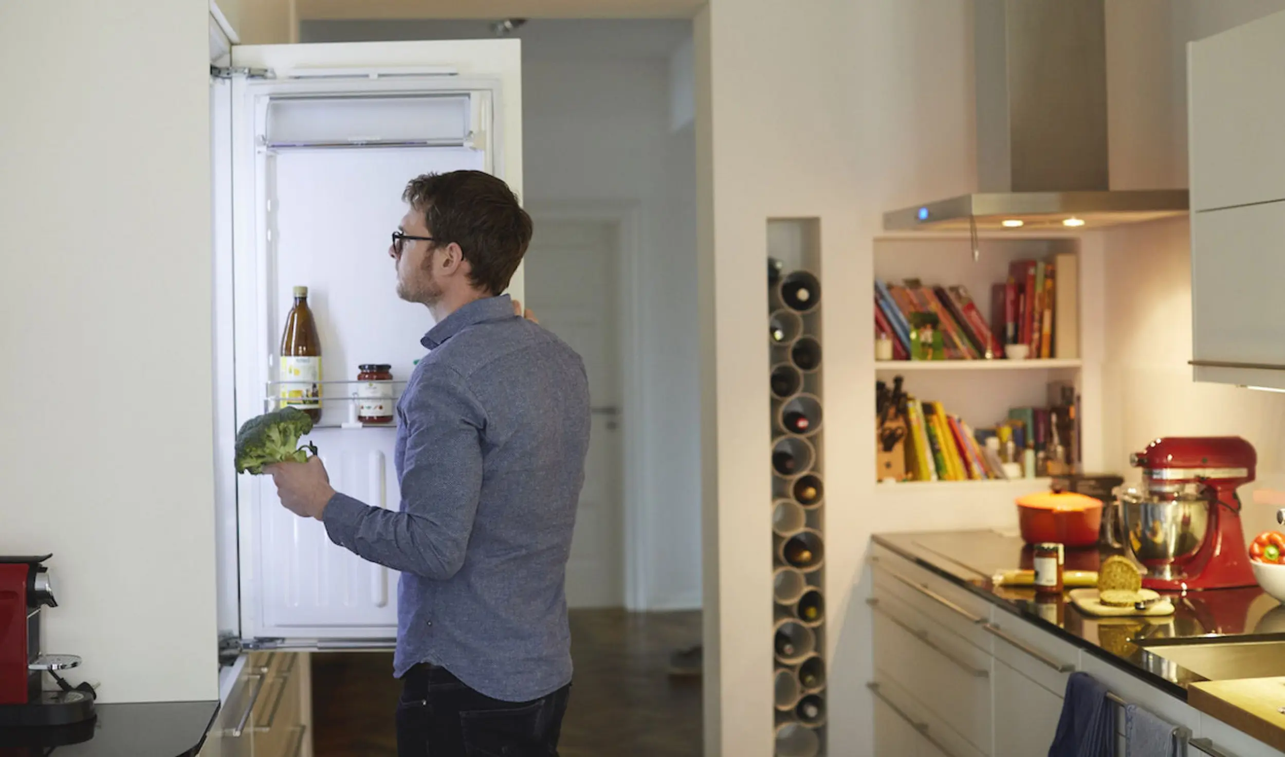 Mann steht vor Kühlschrank