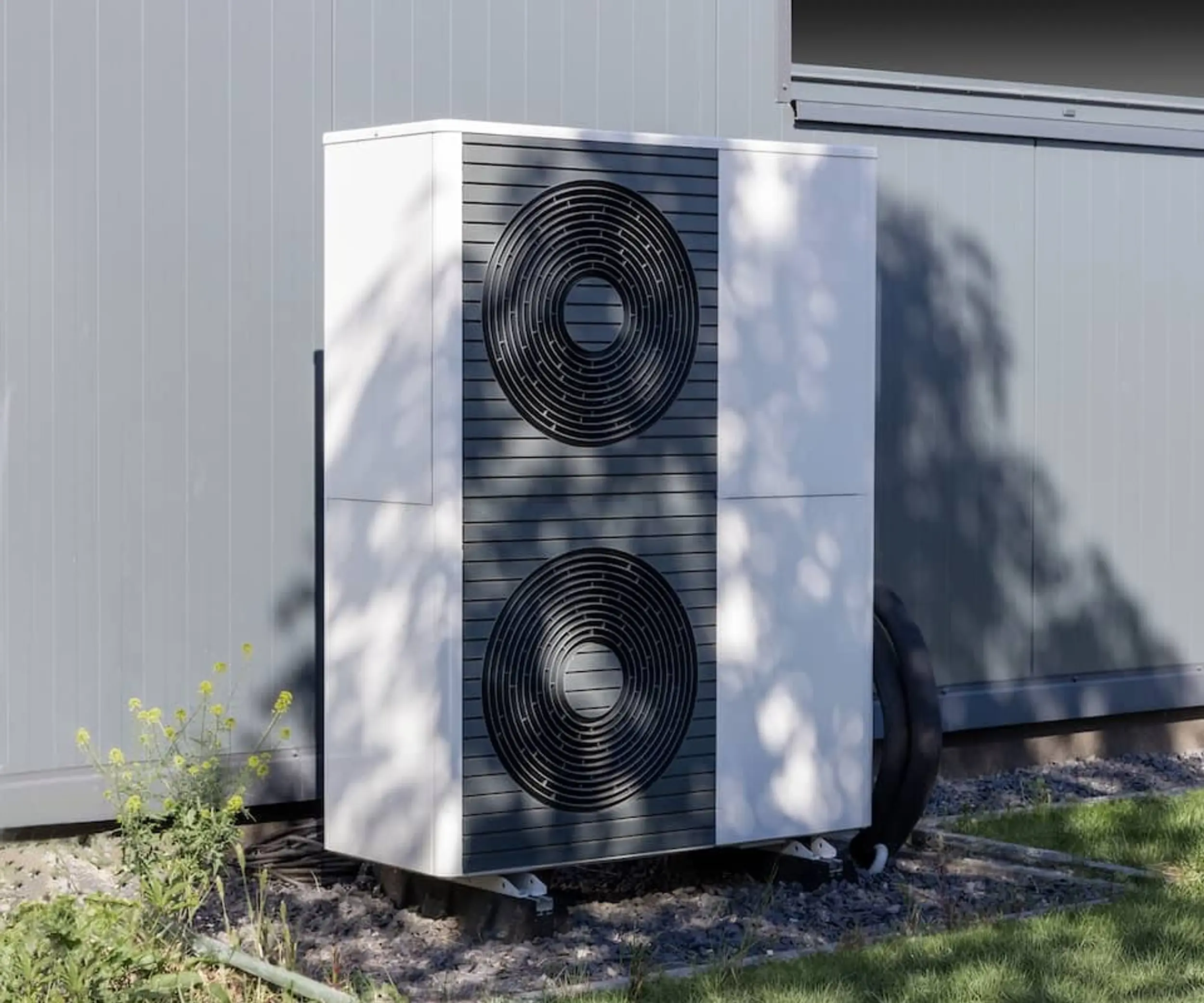 Eine Wärmepumpe steht vor einem Wohnhaus an der Wand