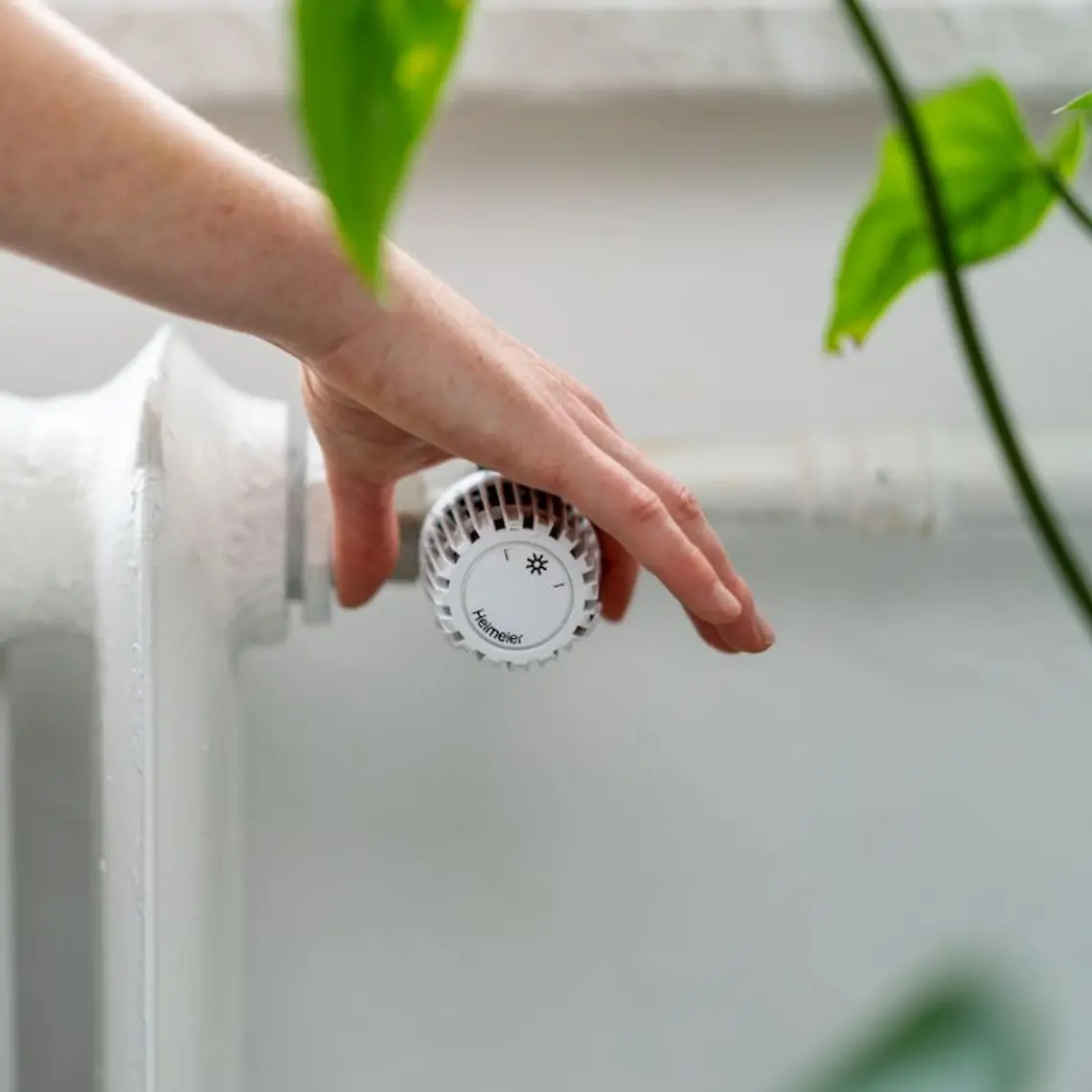 Hand dreht an Thermostat