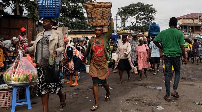 Women carry food on their heads as they walk through the Kantamanto market in downtown. The market is home to more than 30,00 traders, who sell most commonly secondhand clothing, and it the West African hub for used clothing from the west.