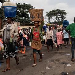 Women carry food on their heads as they walk through the Kantamanto market in downtown. The market is home to more than 30,00 traders, who sell most commonly secondhand clothing, and it the West African hub for used clothing from the west.