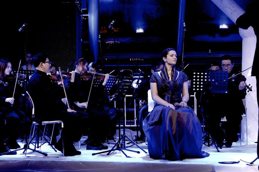 Performance with string players, blue stage lighting.