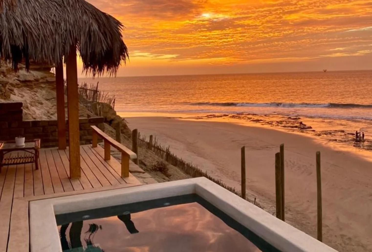 Piscina y océano de Villa La Vista bajo un cielo de atardecer.