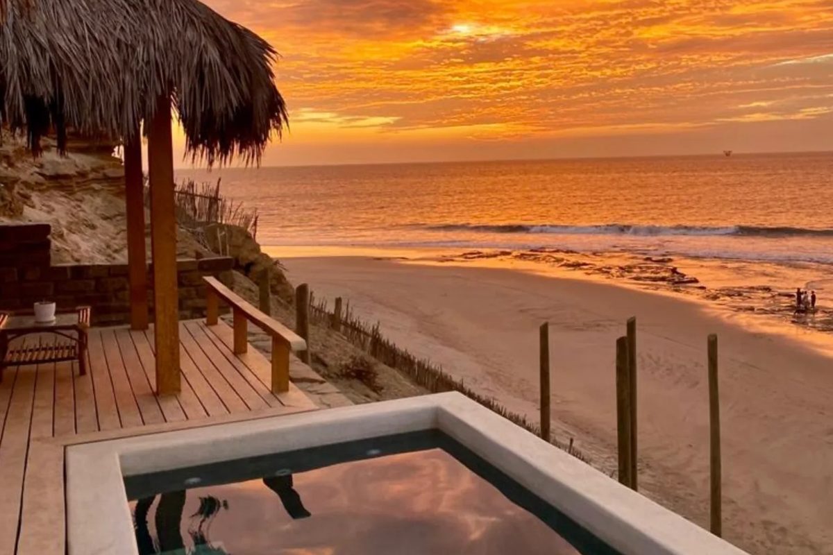 Piscina y océano de Villa La Vista bajo un cielo de atardecer.