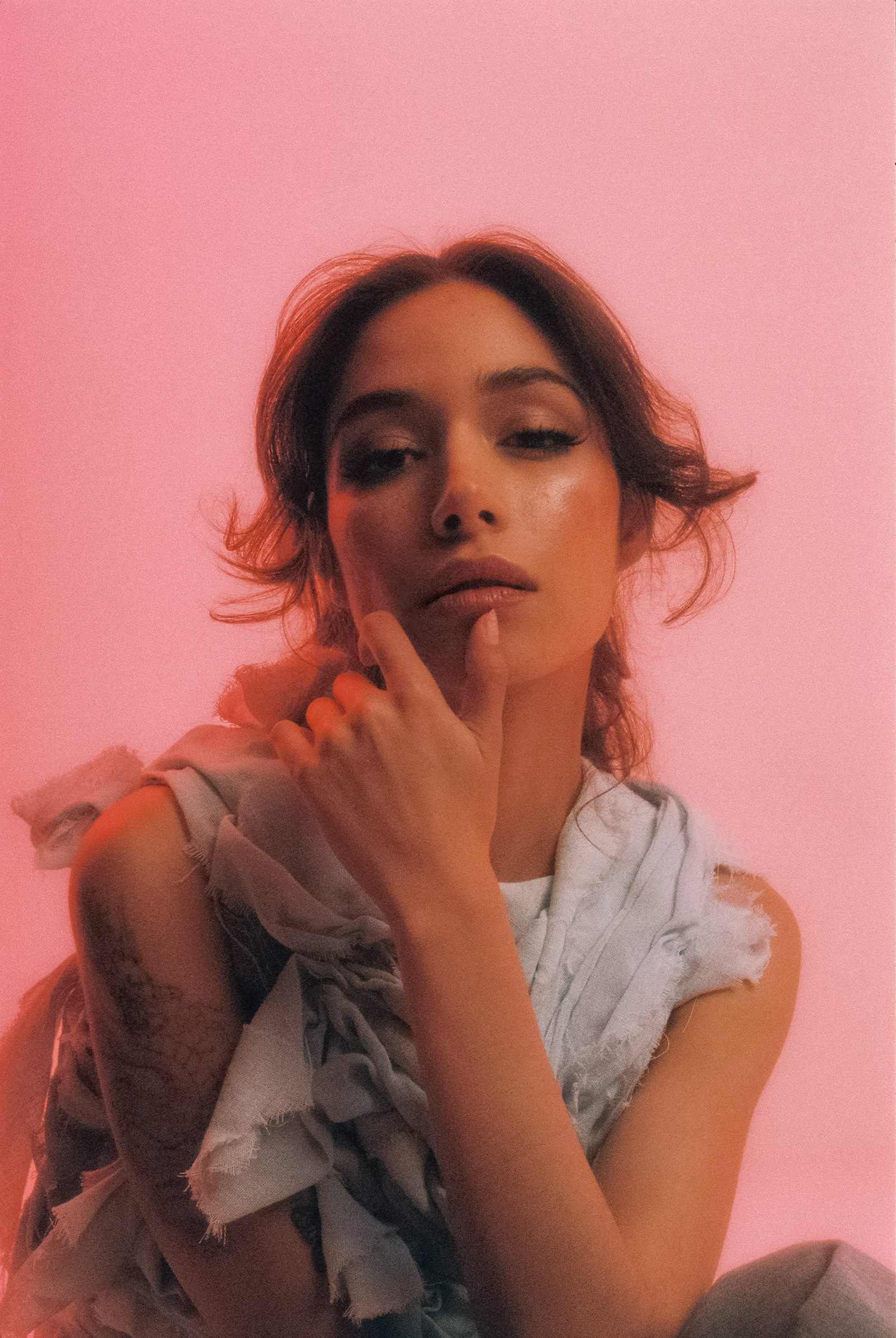 Close-up studio portrait of Michelle Malacara in a pale textured fabric top, photographed on film with soft pink light.