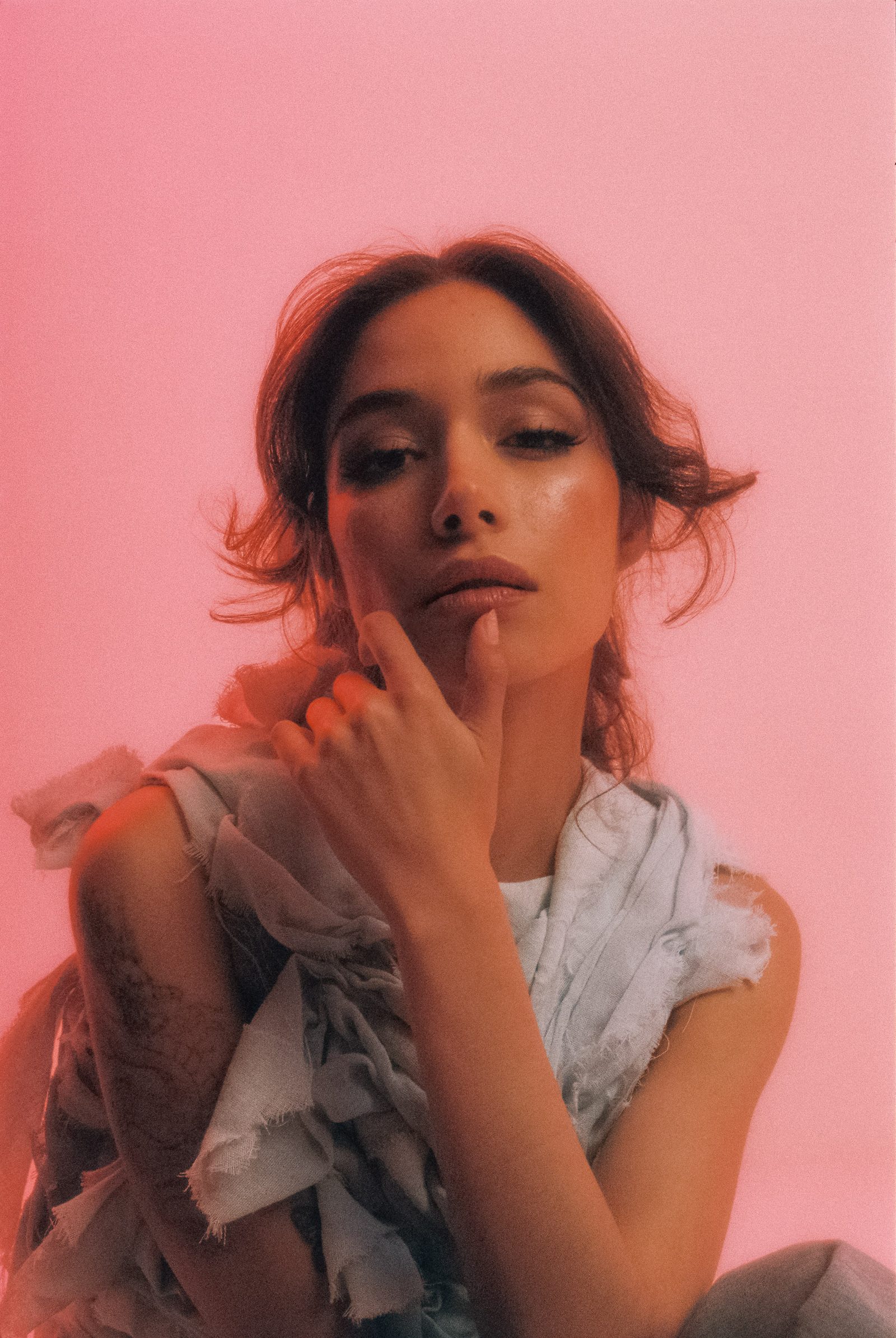 Close-up studio portrait of Michelle Malacara in a pale textured fabric top, photographed on film with soft pink light.