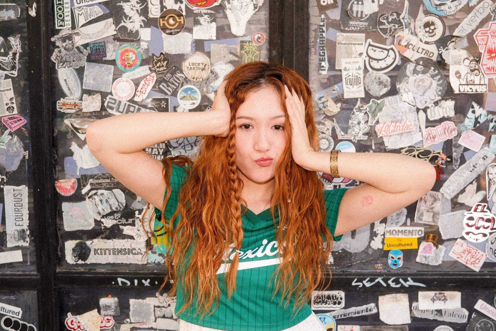 A redhaired girl dressed in Mexico's colors playing with her hair