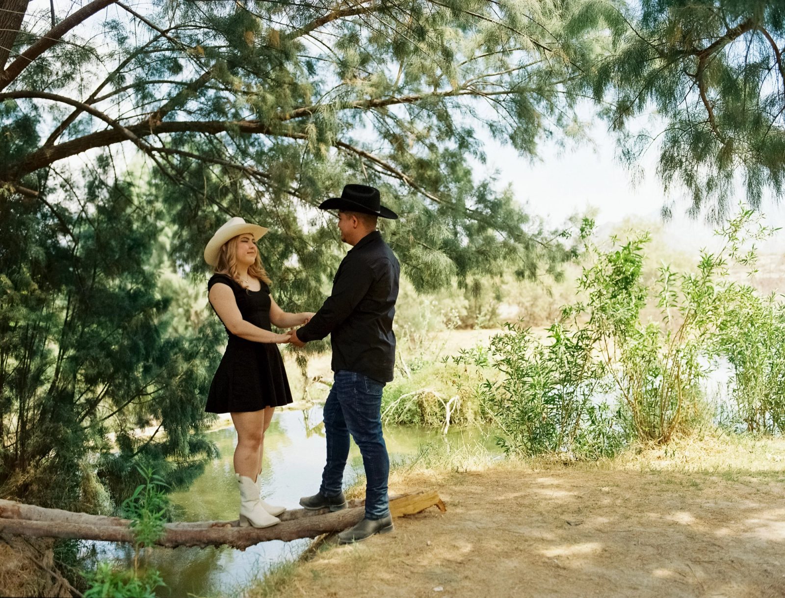 Western styled couple under a tree by the river