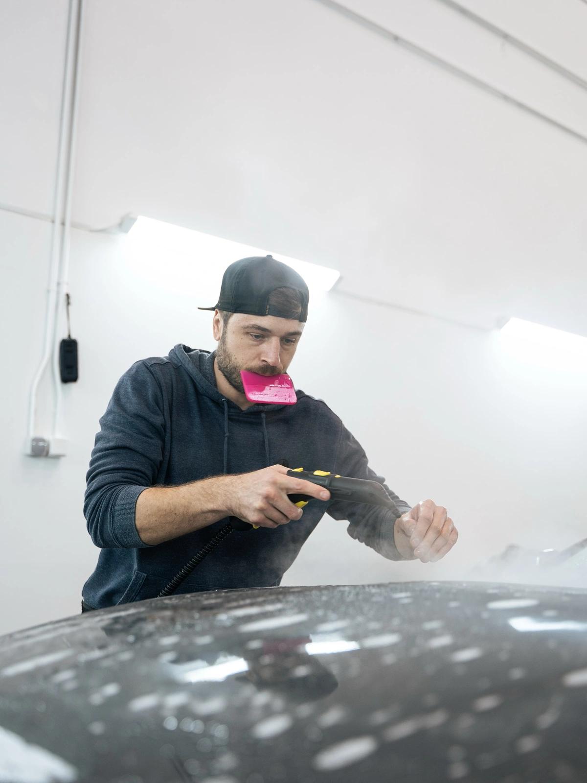 Especialista utilizando pistola de agua durante un servicio de car wrap en el taller de aboutwrap garage.