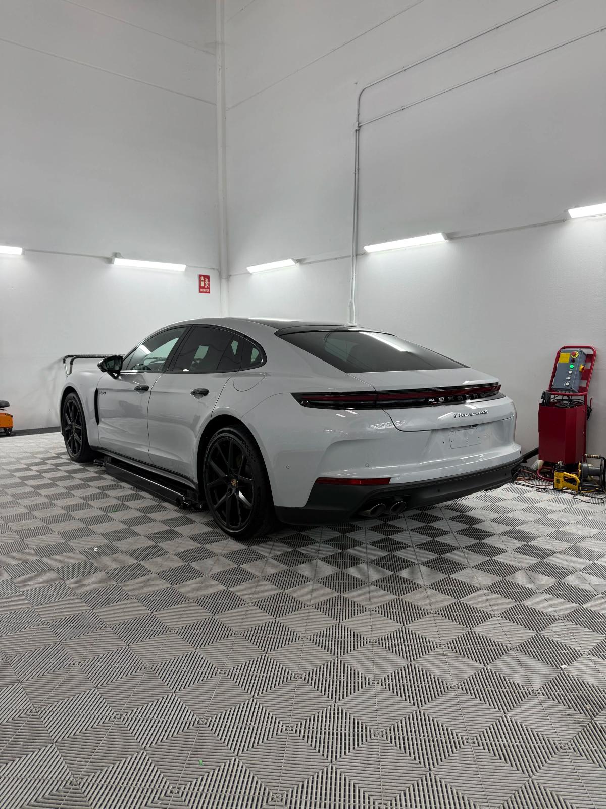 Vista trasera de un Porsche Panamera de color blanco en el estudio de detailing de aboutwrap garage.