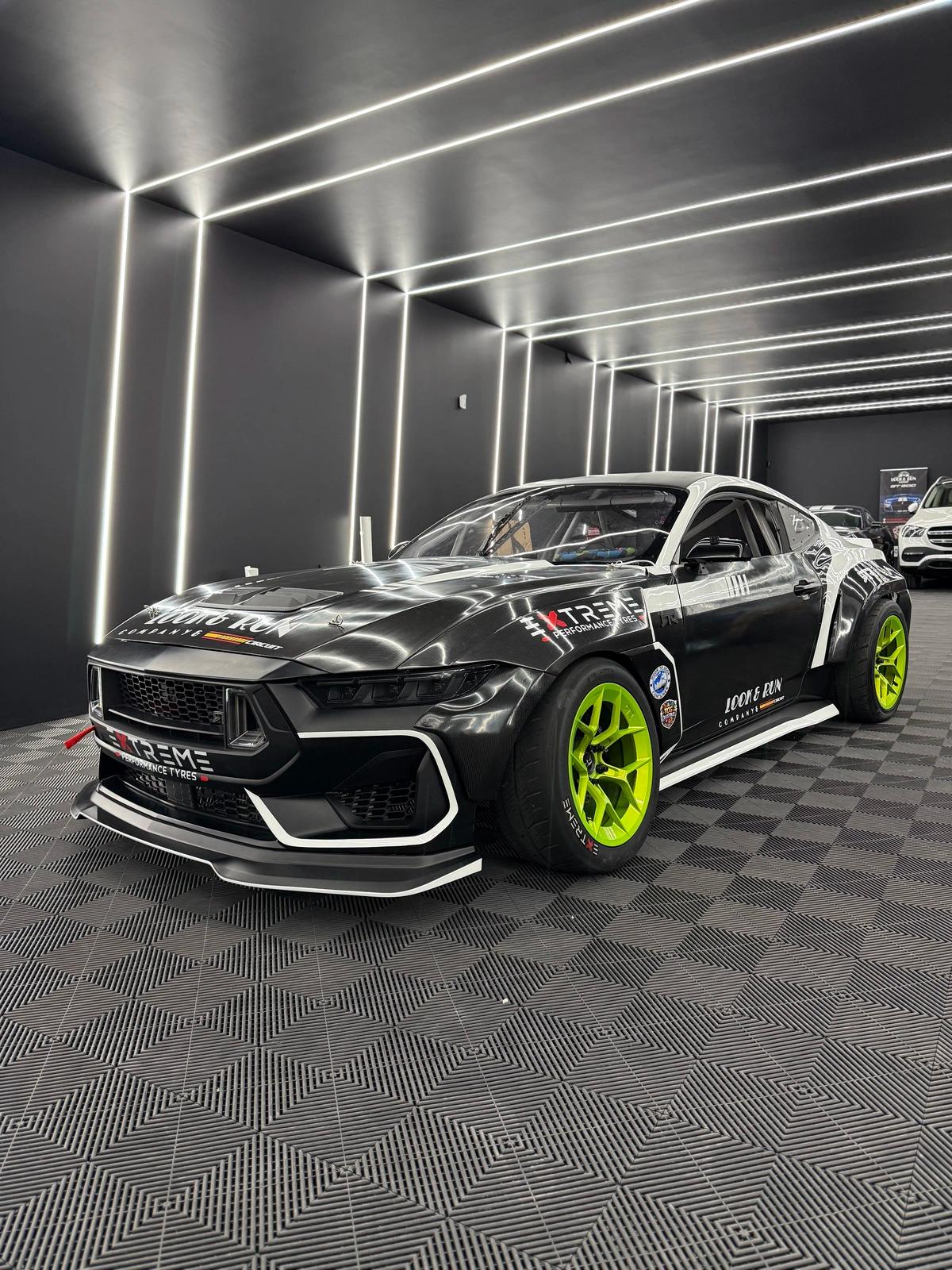Coche de competición modificado con kit de carrocería ensanchada y llantas verde flúor en aboutwrap garage.