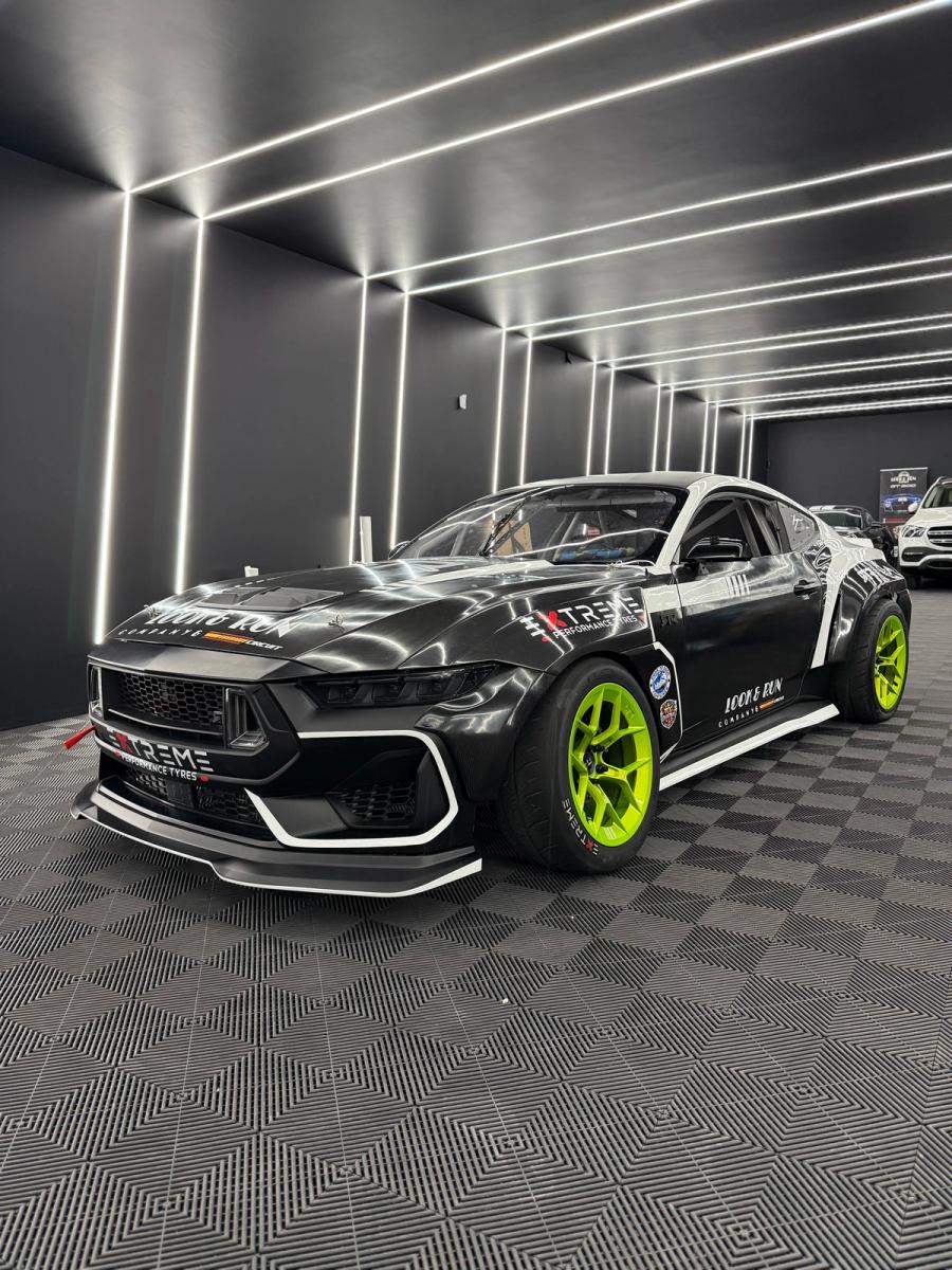Coche de competición modificado con kit de carrocería ensanchada y llantas verde flúor en aboutwrap garage.