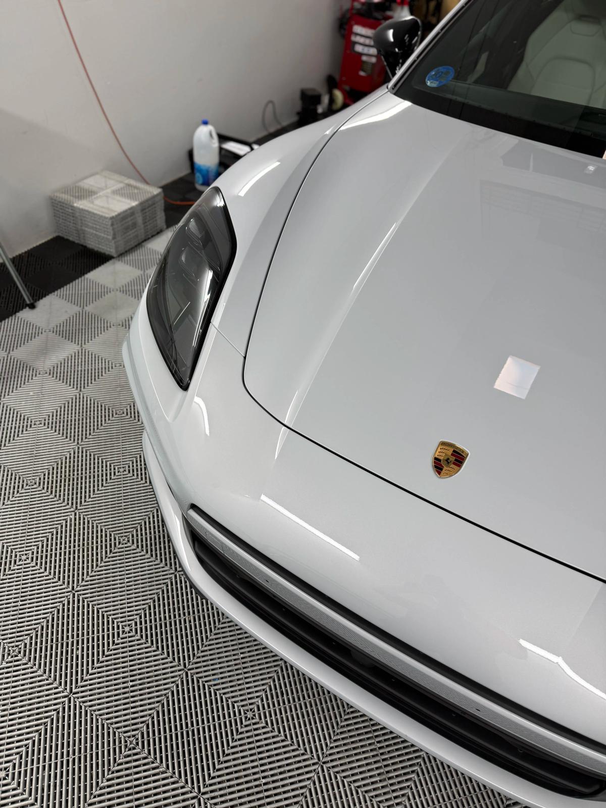 Detalle del capó, emblema y faro delantero LED de un Porsche deportivo en aboutwrap garage.