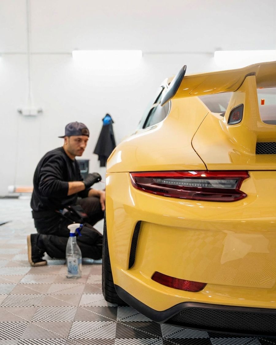 Profesional de aboutwrap aplicando PPF de alta calidad a un Porsche Amarillo