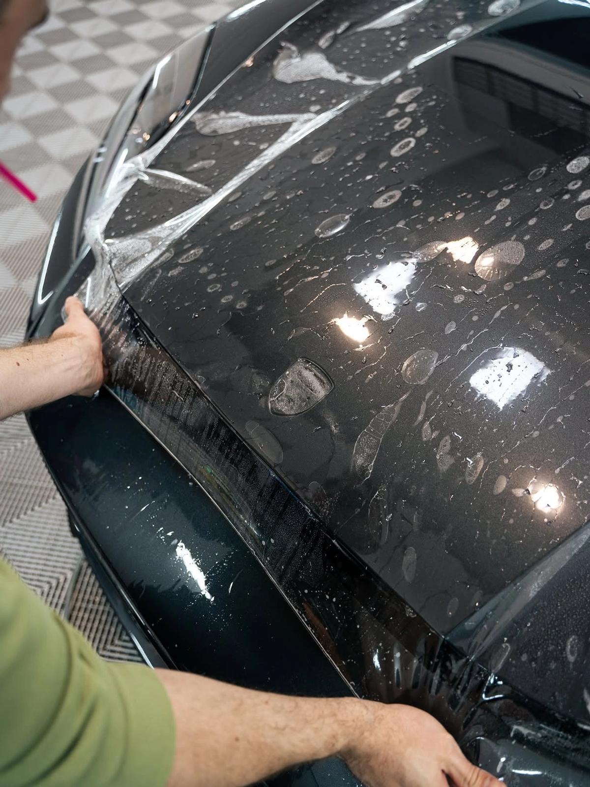  Instalación húmeda de lámina PPF sobre el capó oscuro de un deportivo en aboutwrap garage.