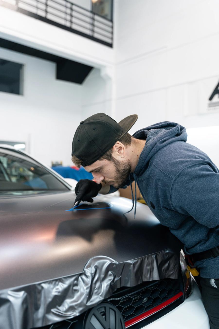 Marcaje con cinta de corte y bisturí sobre el capó de un coche en el estudio de aboutwrap garage.