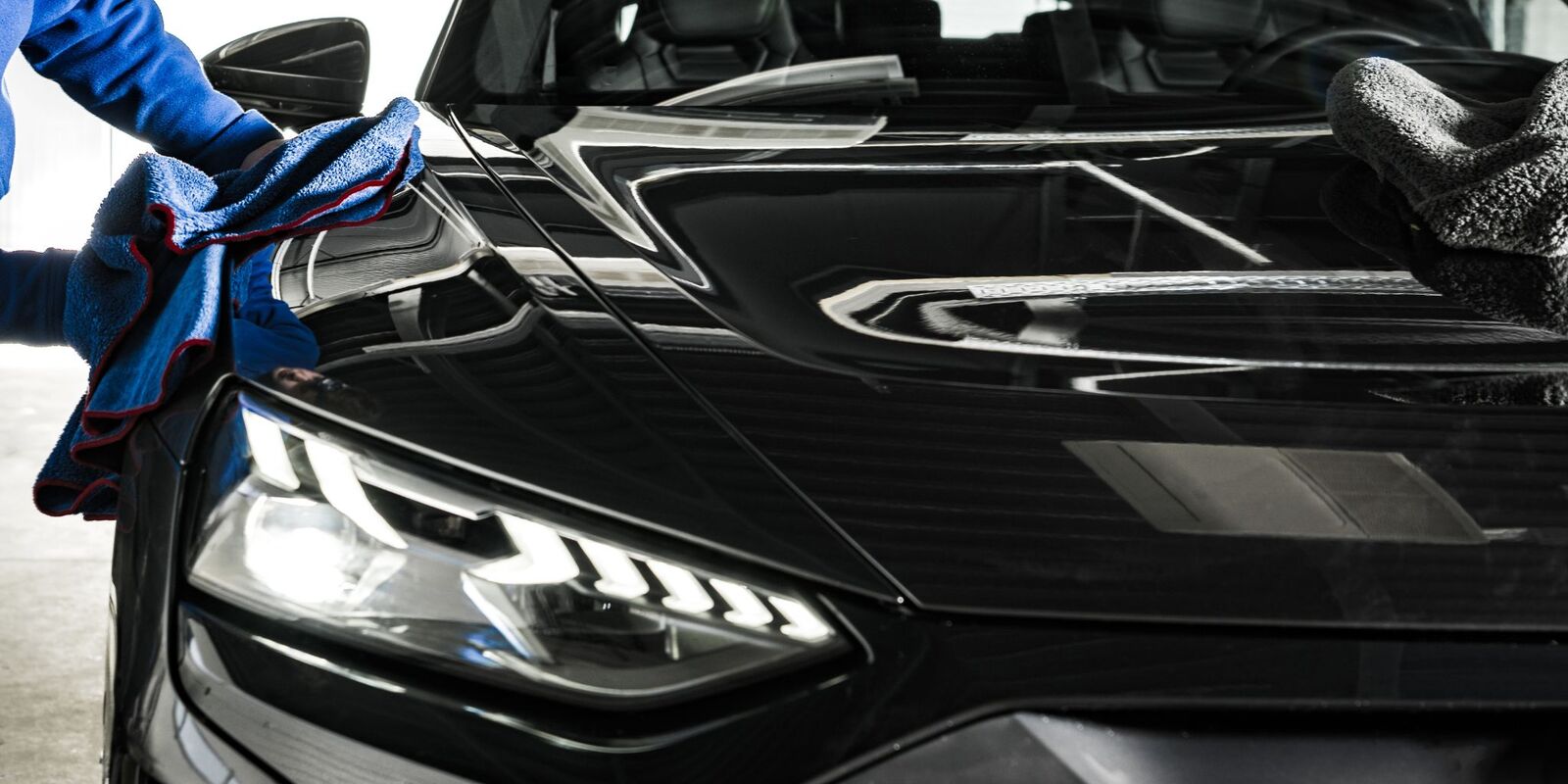 Gloved hand wiping the hood of a black car