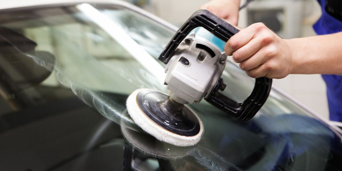 Hand polisher working on a car windshield
