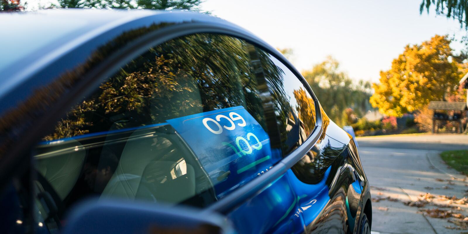 Eco Car Cafe lettering reflected in the glossy side window of a dark blue car