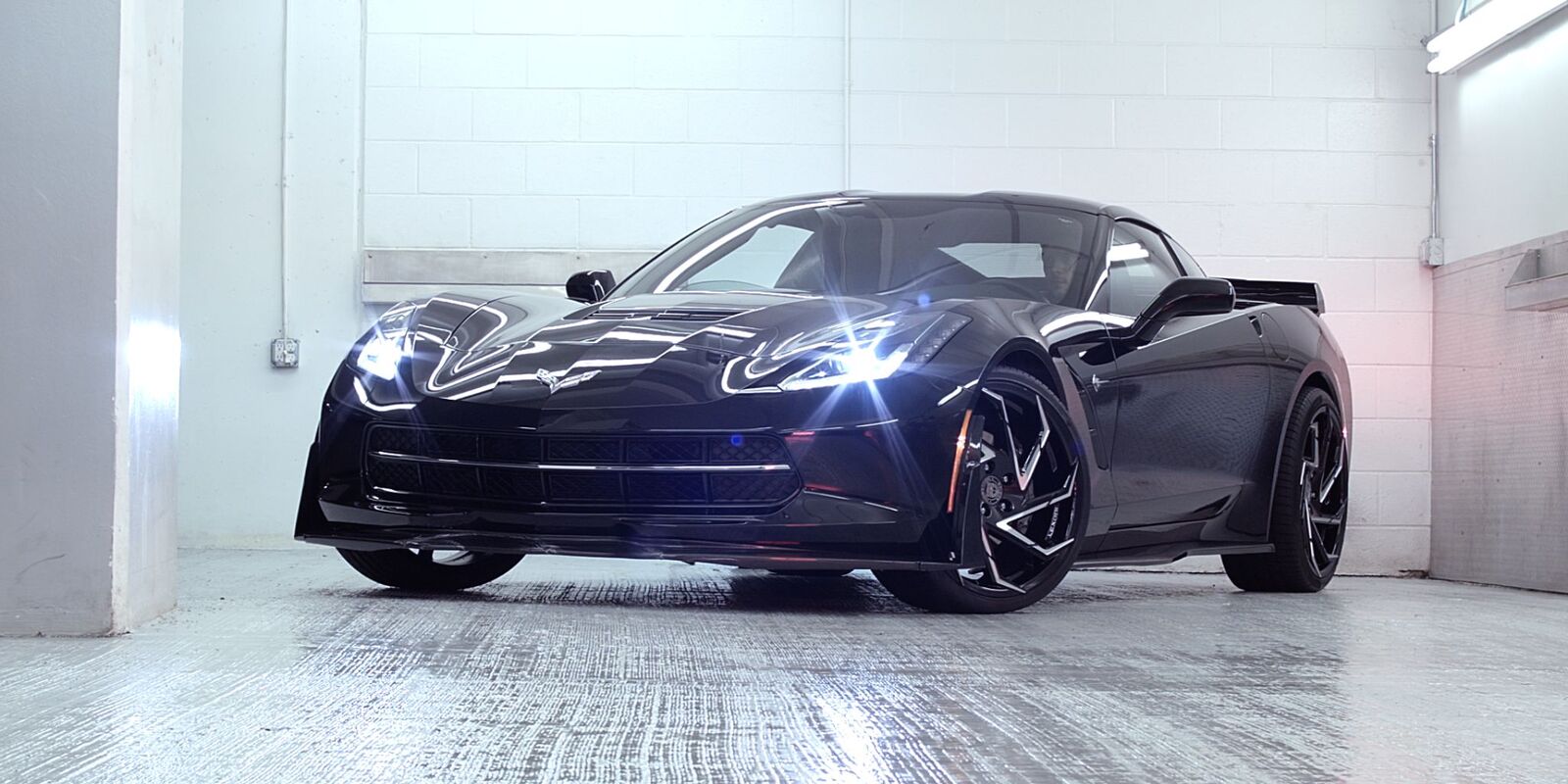 Dark sports car in a white studio bay