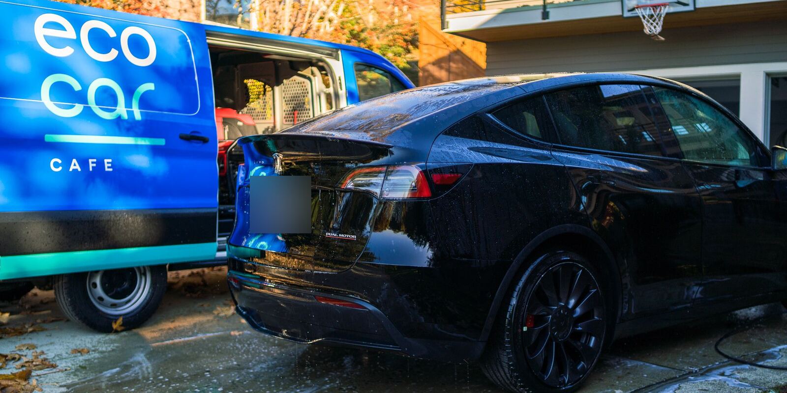 Black Tesla after a hand wash beside an Eco Car Cafe mobile van