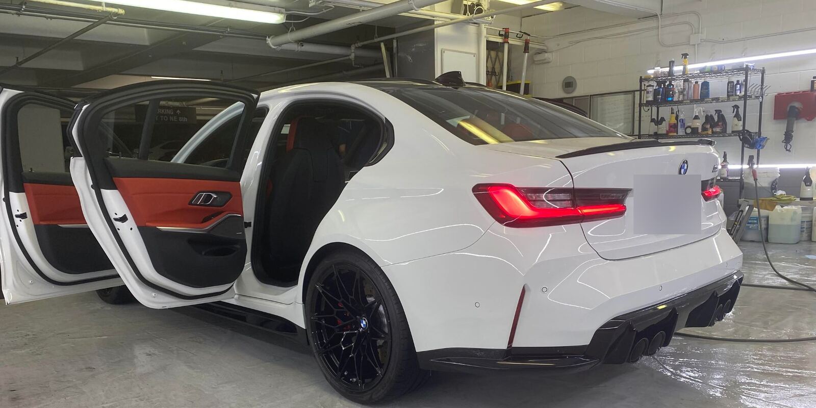 White BMW sedan with doors open in the Eco Car Cafe shop bay