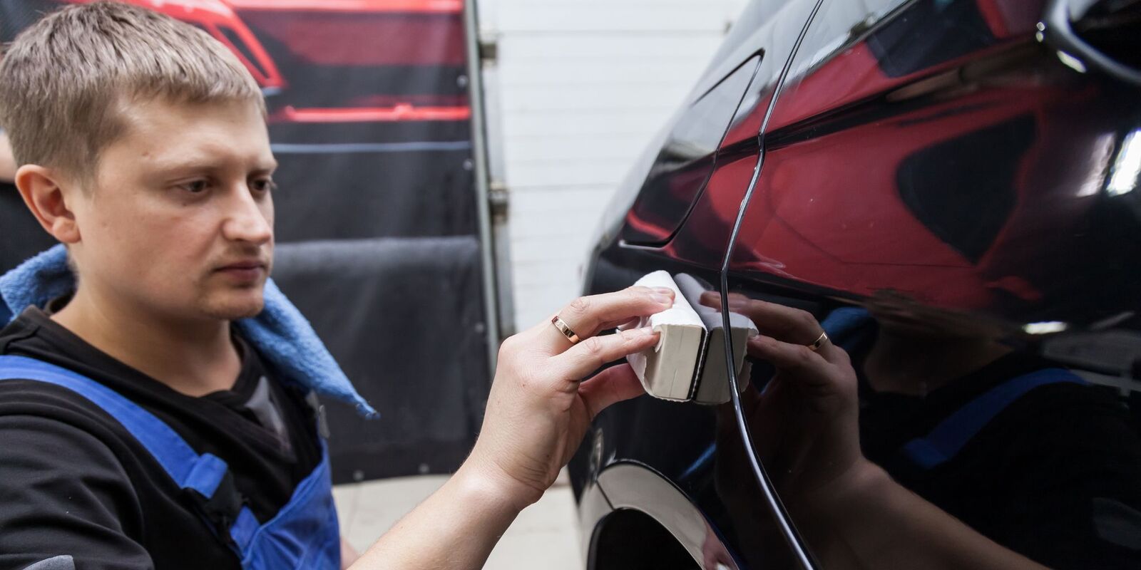 Man applying wax to a dark car with a pad