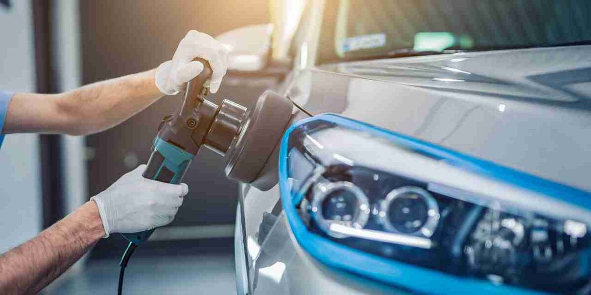 Polisher buffing a silver car beside its headlight