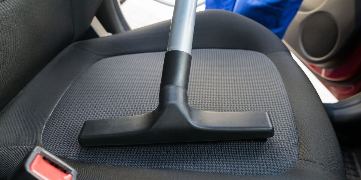 Vacuum nozzle cleaning a dark fabric car seat