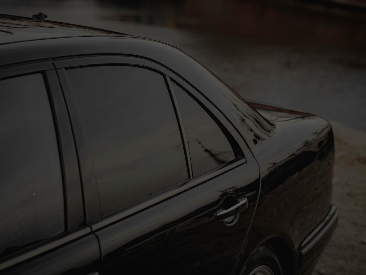 Dark tinted side windows on a black sedan