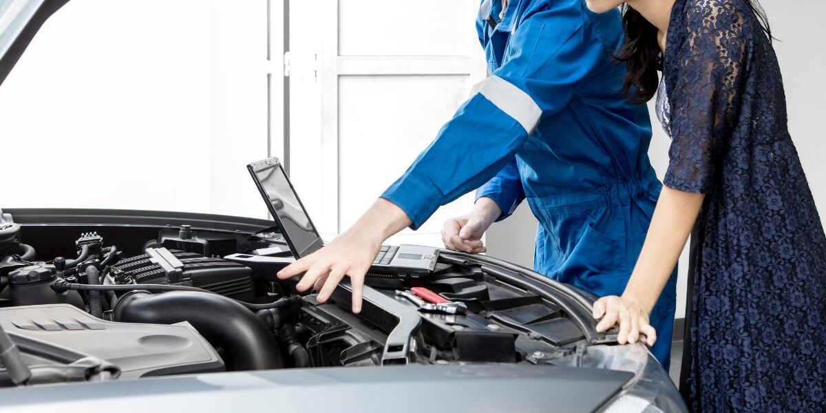 Two people looking under a car hood