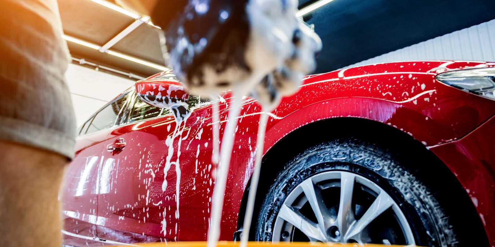 Foam pouring over a red car wheel and fender