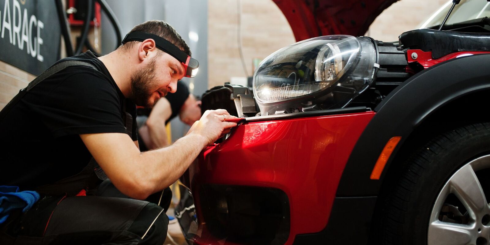 Man fitting a protective panel on a car front end