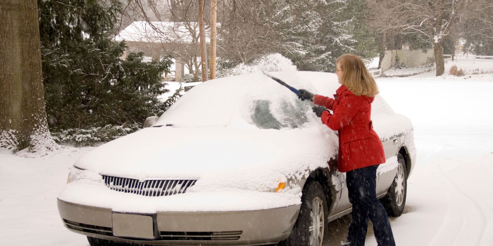 Woman brushing snow off a car