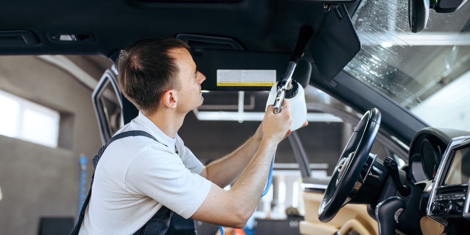 Technician in overalls cleaning a car interior
