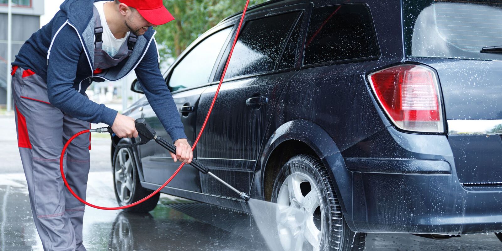 Man pressure washing a dark wagon