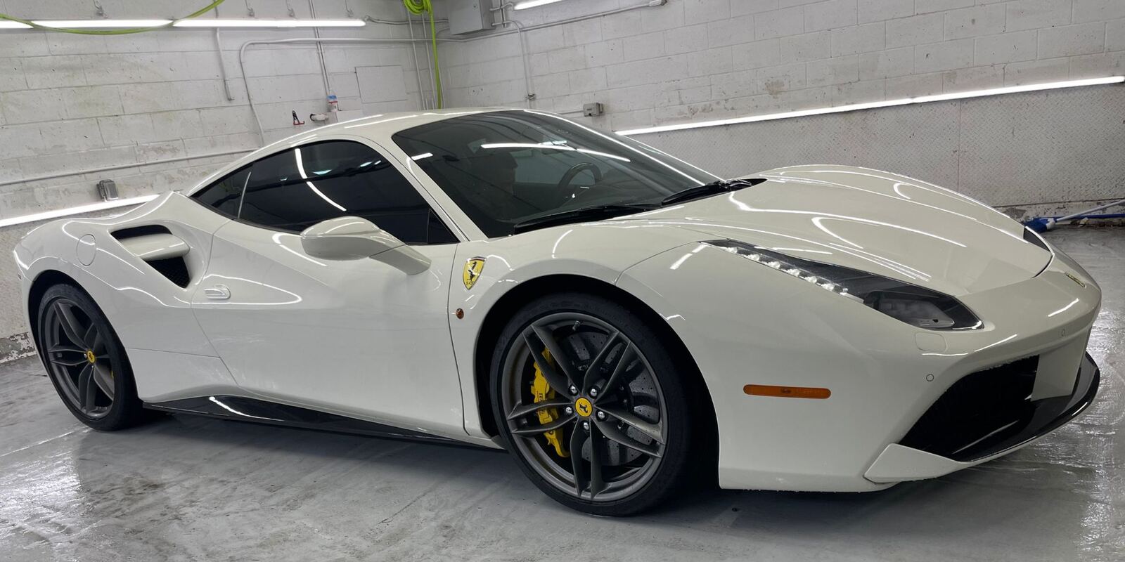 White Ferrari with a glossy finish parked in the studio bay