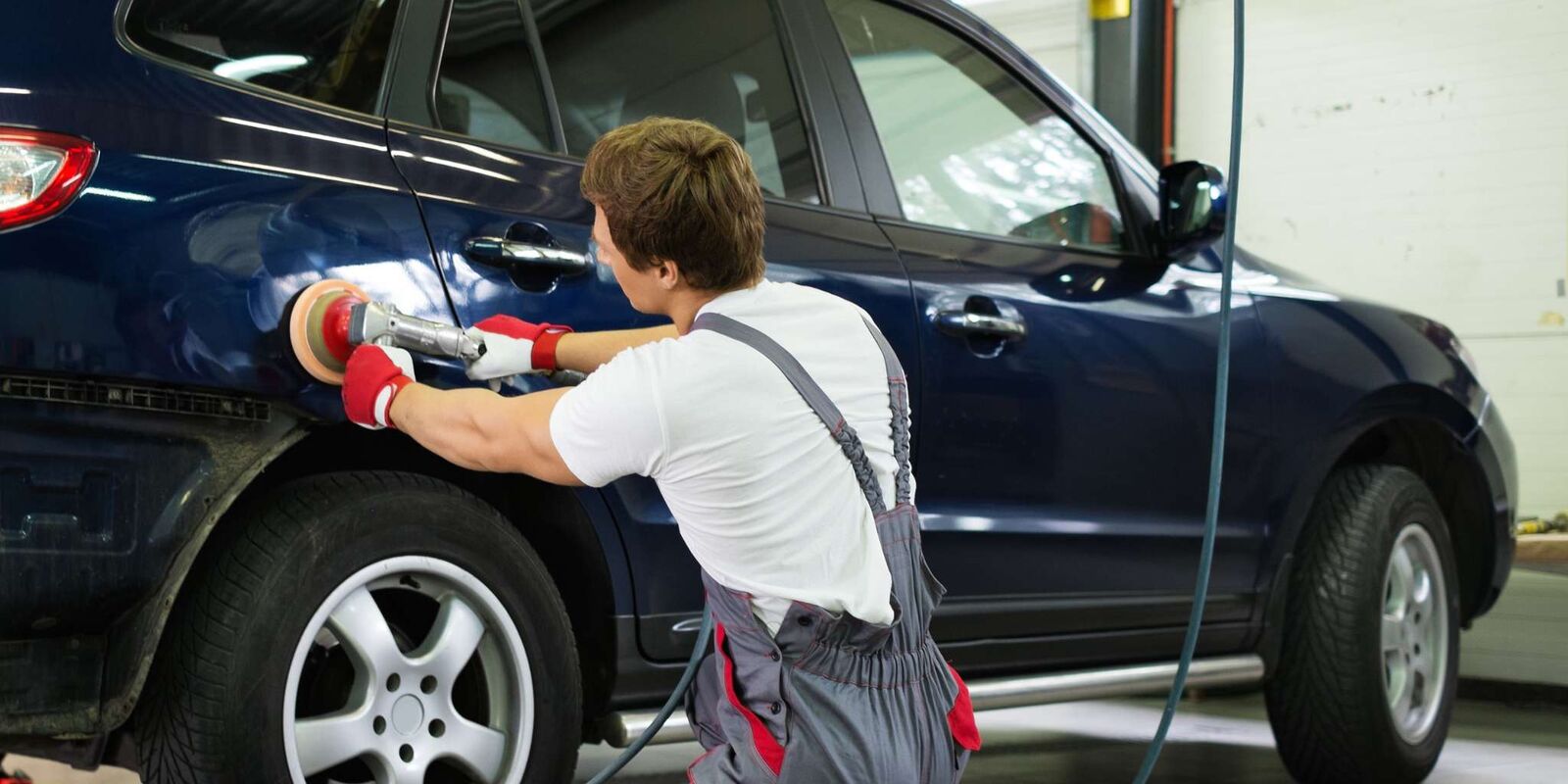 Technician polishing a blue SUV door