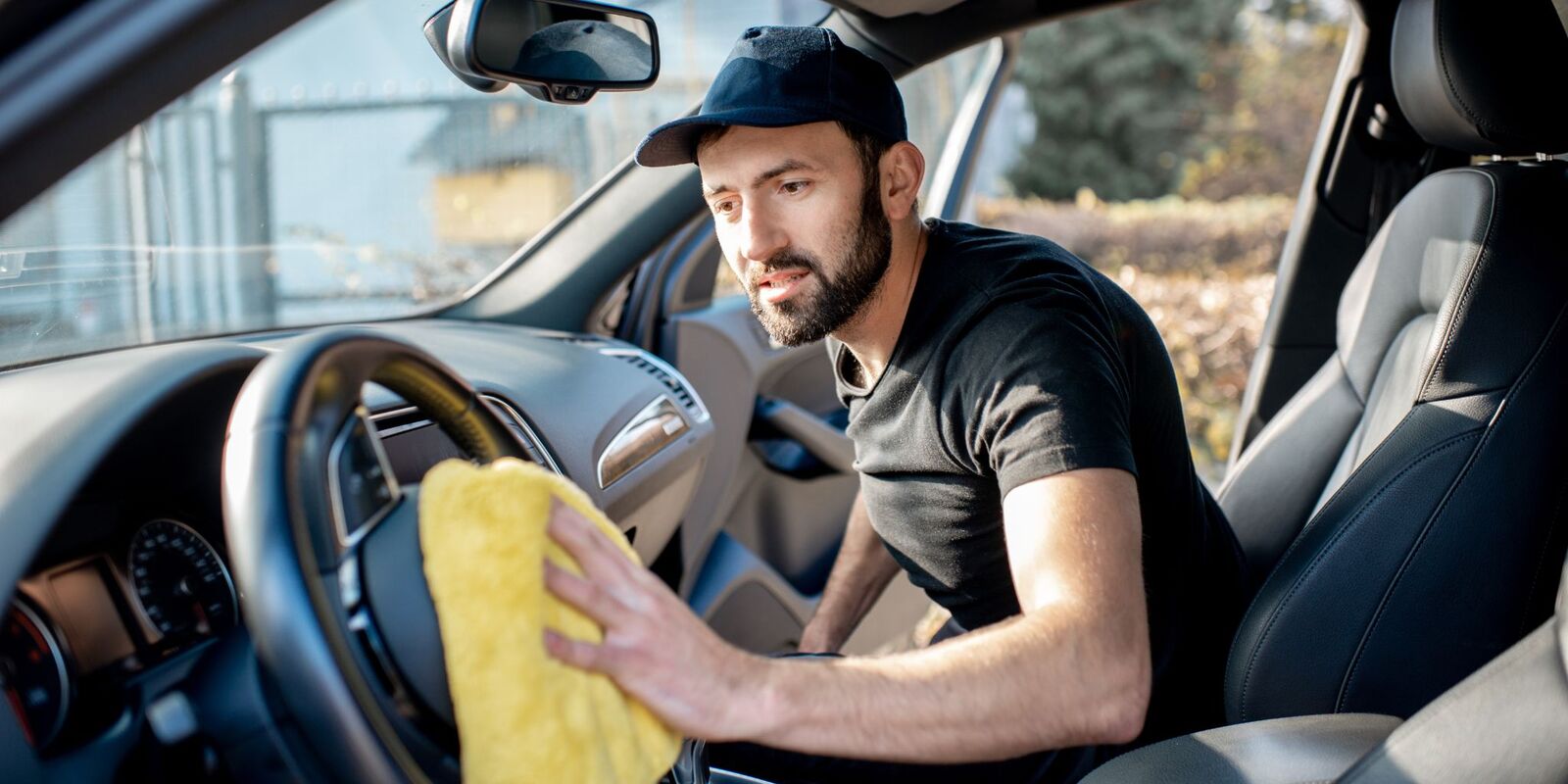 Man wiping a steering wheel with a yellow cloth