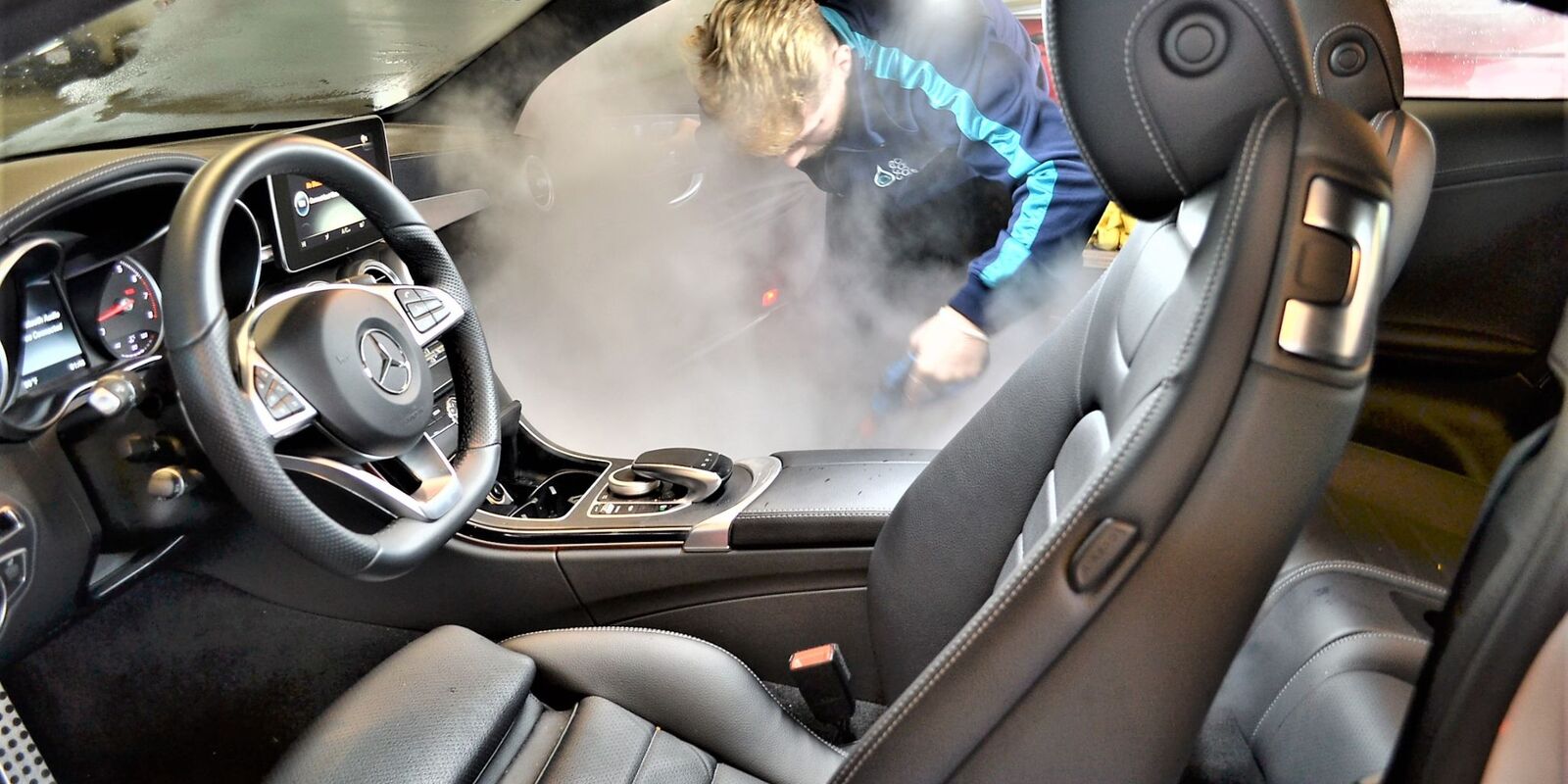 Technician steam cleaning a Mercedes interior